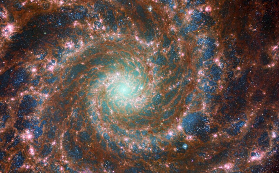 M74 shines at its brightest in this combined optical/mid-infrared image, featuring data from both the NASA/ESA Hubble Space Telescope and the NASA/ESA/CSA James Webb Space Telescope. With Hubble’s venerable Advanced Camera for Surveys (ACS) and Webb’s powerful Mid-InfraRed Instrument (MIRI) capturing a range of wavelengths, this new image has remarkable depth. The red colours mark dust threaded through the arms of the galaxy, lighter oranges being areas of hotter dust. The young stars throughout the arms and the nuclear core are picked out in blue. Heavier, older stars towards the galaxy’s centre are shown in cyan and green, projecting a spooky glow from the core of the Phantom Galaxy. Bubbles of star formation are also visible in pink across the arms. Such a variety of galactic features is rare to see in a single image. Scientists combine data from telescopes operating across the electromagnetic spectrum to truly understand astronomical objects. In this way, data from Hubble and Webb compliment each other to provide a comprehensive view of the spectacular M74 galaxy. Links  Pan of the Phantom Galaxy Hubble and Webb Showcase M74 Pan of Combined optical/mid-infrared image of M74 (Hubble and Webb) Image A Image C